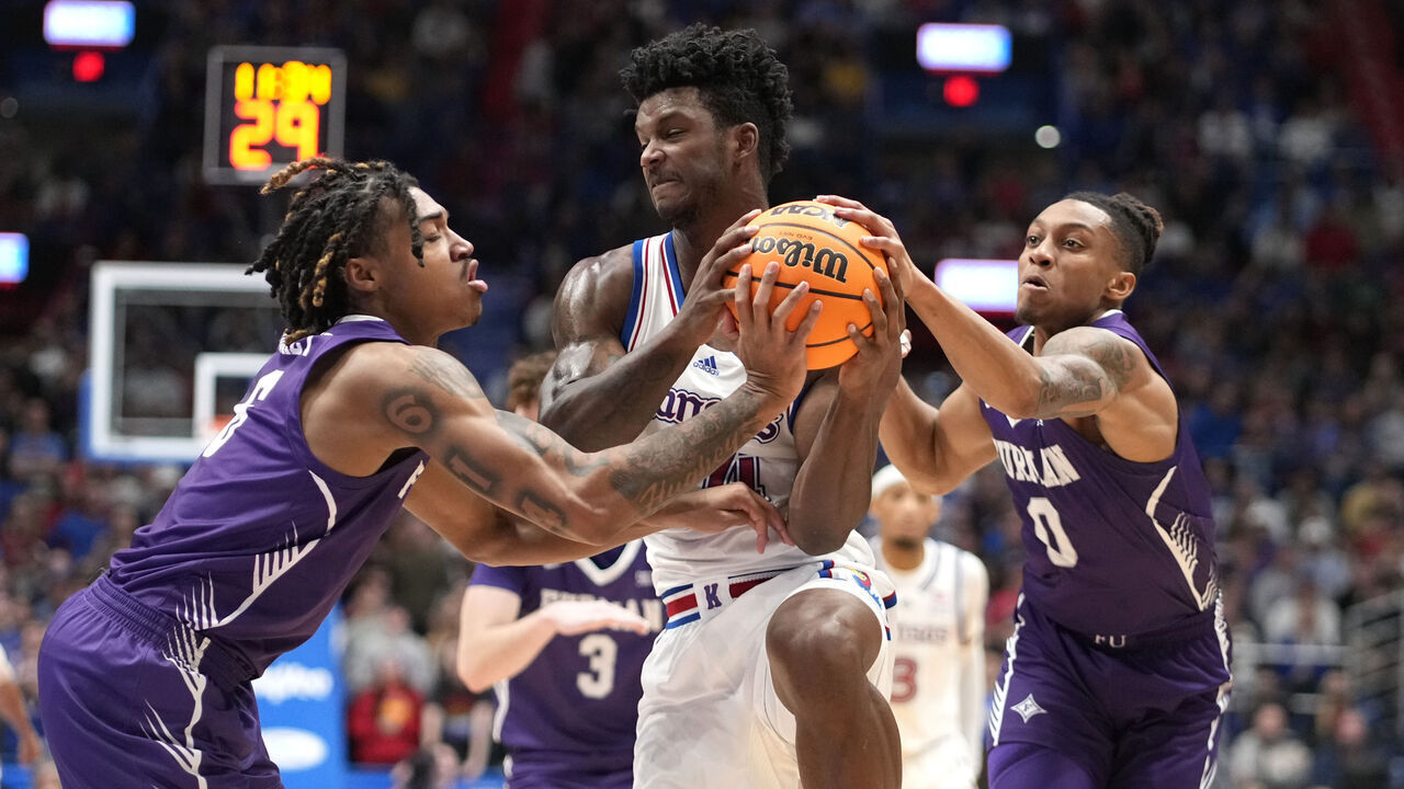 LAWRENCE, KANSAS - NOVEMBER 30: KJ Adams Jr. #24 of the Kansas Jayhawks battle for the ball against Tyrese Hughey #6 and PJay Smith Jr. #0 of the Furman Paladins in the first half at Allen Fieldhouse on November 30, 2024 in Lawrence, Kansas.