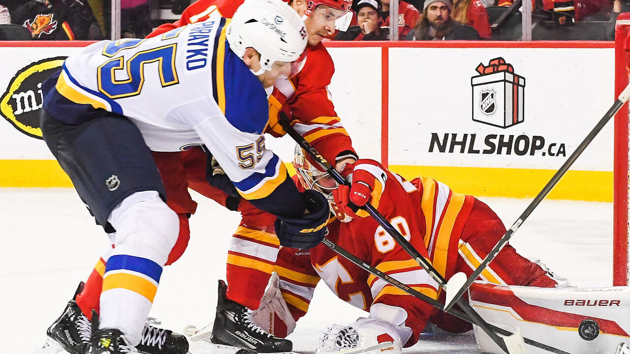 CALGARY, CANADA - DECEMBER 5: Colton Parayko #55 of the St Louis Blues scores on Daniel Vladar #80 of the Calgary Flames during the overtime period of an NHL game at Scotiabank Saddledome on December 5, 2024 in Calgary, Alberta, Canada.