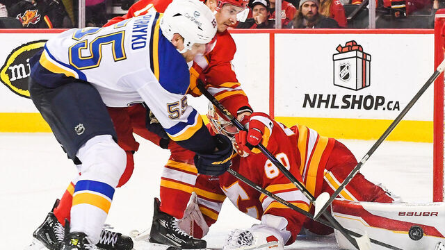 CALGARY, CANADA - DECEMBER 5: Colton Parayko #55 of the St Louis Blues scores on Daniel Vladar #80 of the Calgary Flames during the overtime period of an NHL game at Scotiabank Saddledome on December 5, 2024 in Calgary, Alberta, Canada.