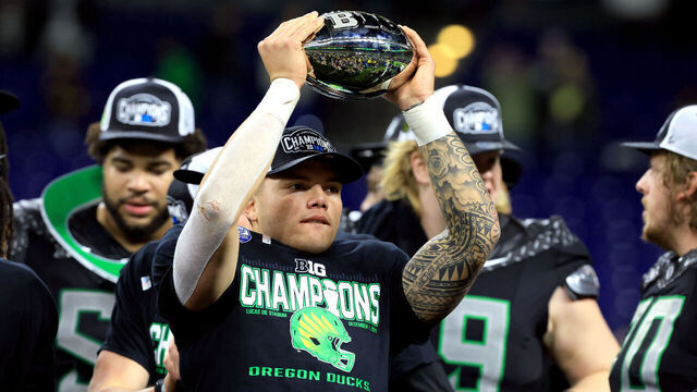INDIANAPOLIS, INDIANA - DECEMBER 07: Dillon Gabriel #8 of the Oregon Ducks celebrates with the trophy after the team's 45-37 win against the Penn State Nittany Lions in the 2024 Big Ten Football Championship at Lucas Oil Stadium on December 07, 2024 in Indianapolis, Indiana.