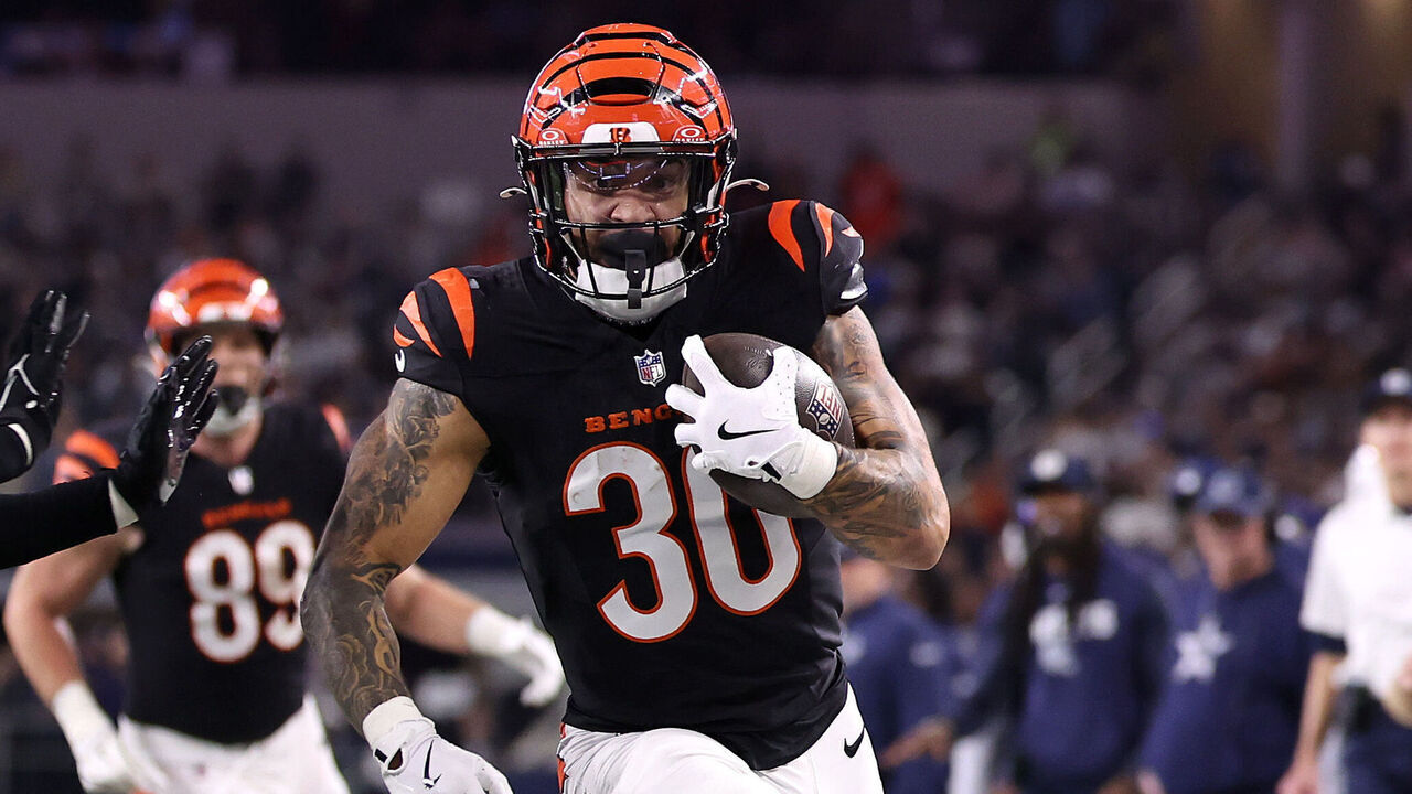 ARLINGTON, TEXAS - DECEMBER 09: Chase Brown #30 of the Cincinnati Bengals runs the ball to score a 16 yard touchdown against Donovan Wilson #6 of the Dallas Cowboys during the second quarter in the game at AT&T Stadium on December 09, 2024 in Arlington, Texas.