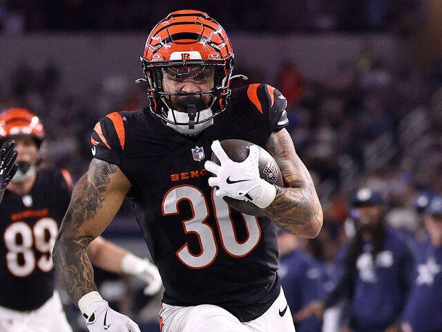 ARLINGTON, TEXAS - DECEMBER 09: Chase Brown #30 of the Cincinnati Bengals runs the ball to score a 16 yard touchdown against Donovan Wilson #6 of the Dallas Cowboys during the second quarter in the game at AT&T Stadium on December 09, 2024 in Arlington, Texas.