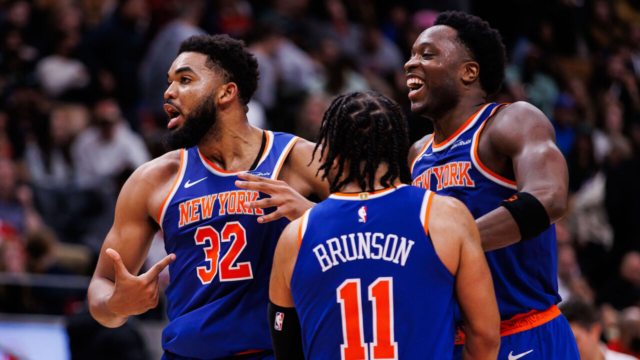 TORONTO, CANADA - DECEMBER 9: Karl-Anthony Towns #32 of the New York Knicks points to his jersey as he celebrates a basket with Jalen Brunson #11 and OG Anunoby #8 during second half of their NBA game against the Toronto Raptors at Scotiabank Arena on December 9, 2024 in Toronto, Canada.