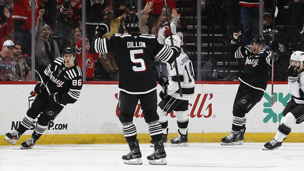 NEWARK, NEW JERSEY - DECEMBER 12: Jack Hughes #86 of the New Jersey Devils reacts with Brenden Dillon #5 and Ondrej Palat #18 of the New Jersey Devils after scoring a goal during the third period against the Los Angeles Kings at Prudential Center on December 12, 2024 in Newark, New Jersey. The Devils won 3-1.