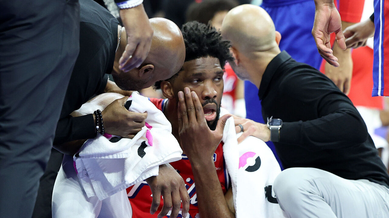 PHILADELPHIA, PENNSYLVANIA - DECEMBER 13: Trainers tend to Joel Embiid #21 of the Philadelphia 76ers during the first half against the Indiana Pacers at the Wells Fargo Center on December 13, 2024 in Philadelphia, Pennsylvania.