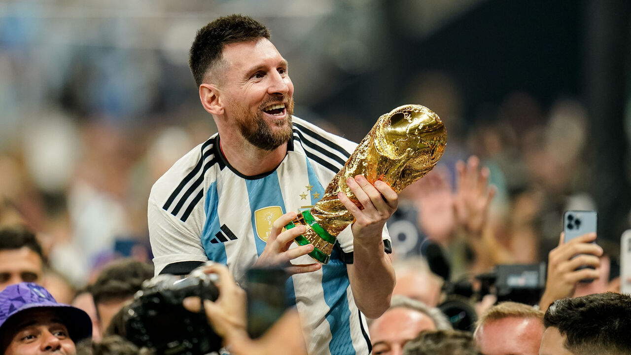 LUSAIL CITY, QATAR - DECEMBER 18: Lionel Messi of Argentina lifts the trophy after winning while sitting on the shoulders of a teammate after the FIFA World Cup Qatar 2022 Final match between Argentina and France at Lusail Stadium on December 18, 2022 in Lusail City, Qatar.