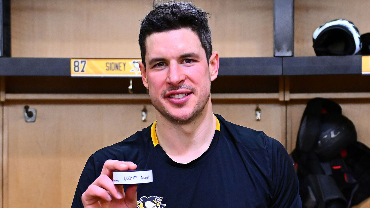 PITTSBURGH, PA - DECEMBER 29: Sidney Crosby #87 of the Pittsburgh Penguins poses with his 1034th career assist puck, after breaking the record for most assists in Penguins history, after the game against the New York Islanders at PPG PAINTS Arena on December 29, 2024 in Pittsburgh, Pennsylvania.