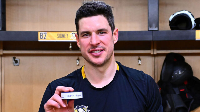 PITTSBURGH, PA - DECEMBER 29: Sidney Crosby #87 of the Pittsburgh Penguins poses with his 1034th career assist puck, after breaking the record for most assists in Penguins history, after the game against the New York Islanders at PPG PAINTS Arena on December 29, 2024 in Pittsburgh, Pennsylvania.