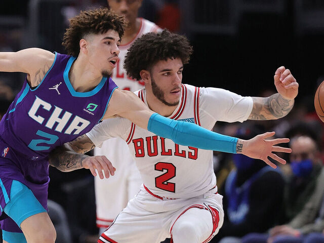 CHICAGO, ILLINOIS - NOVEMBER 29: LaMelo Ball (2) of the Charlotte Hornets and brother Lonzo Ball (2) of the Chicago Bulls chase a loose ball at United Center on November 29, 2021 in Chicago, Illinois.