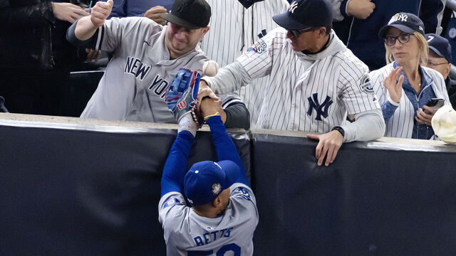 NEW YORK, NEW YORK - OCTOBER 29: Fans Austin Capobianco (L) and John Peter (R) interfere with Mookie Betts #50 of the Los Angeles Dodgers as he attempts to catch a fly ball in foul territory during the first inning of Game Four of the 2024 World Series against the New York Yankees at Yankee Stadium on October 29, 2024 in the Bronx borough of New York City. The play resulted in an out.