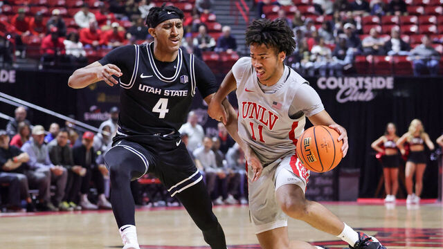 LAS VEGAS, NEVADA - JANUARY 15: Dedan Thomas Jr. #11 of the UNLV Rebels drives against Ian Martinez #4 of the Utah State Aggies in the first half of their game at the Thomas & Mack Center on January 15, 2025 in Las Vegas, Nevada.