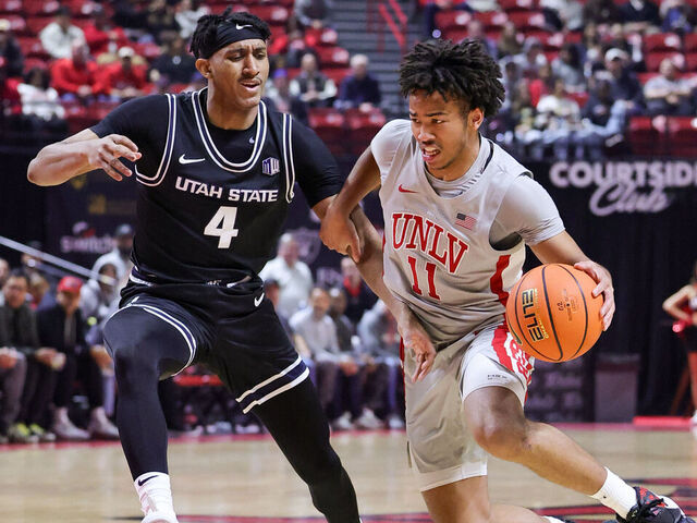 LAS VEGAS, NEVADA - JANUARY 15: Dedan Thomas Jr. #11 of the UNLV Rebels drives against Ian Martinez #4 of the Utah State Aggies in the first half of their game at the Thomas & Mack Center on January 15, 2025 in Las Vegas, Nevada.
