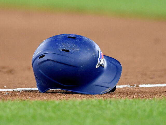 BALTIMORE, MD - AUGUST 23: A close up view of a Toronto Blue Jays bird logo on a batting helmet on the infield dirt with natural turf grass during the Toronto Blue Jays versus Baltimore Orioles MLB game at Orioles Park at Camden Yards on Aug 23, 2023 in Baltimore, MD.