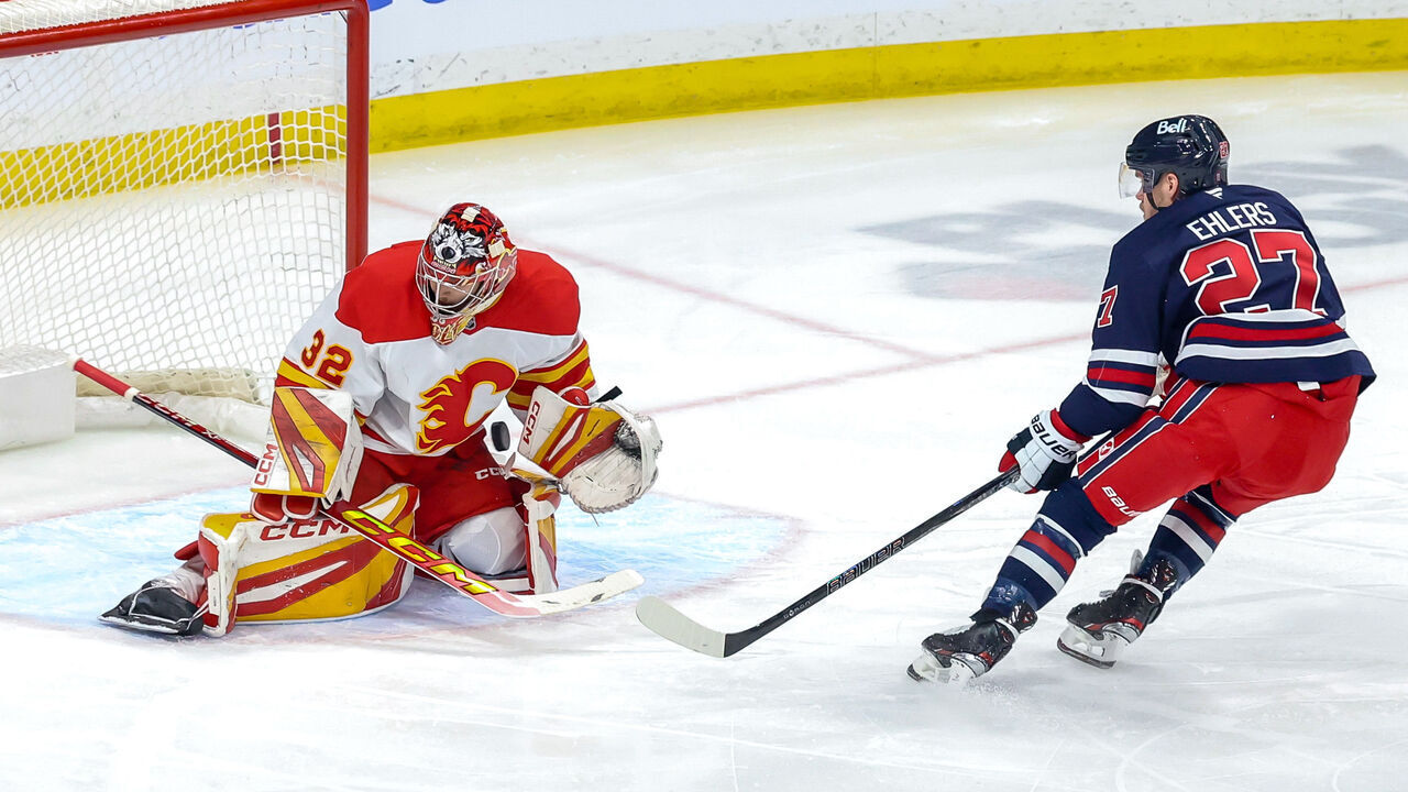 WINNIPEG, CANADA - JANUARY 18: Goaltender Dustin Wolf #32 of the Calgary Flames makes a stop on Nikolaj Ehlers #27 of the Winnipeg Jets during first period action at the Canada Life Centre on January 18, 2025 in Winnipeg, Manitoba, Canada.