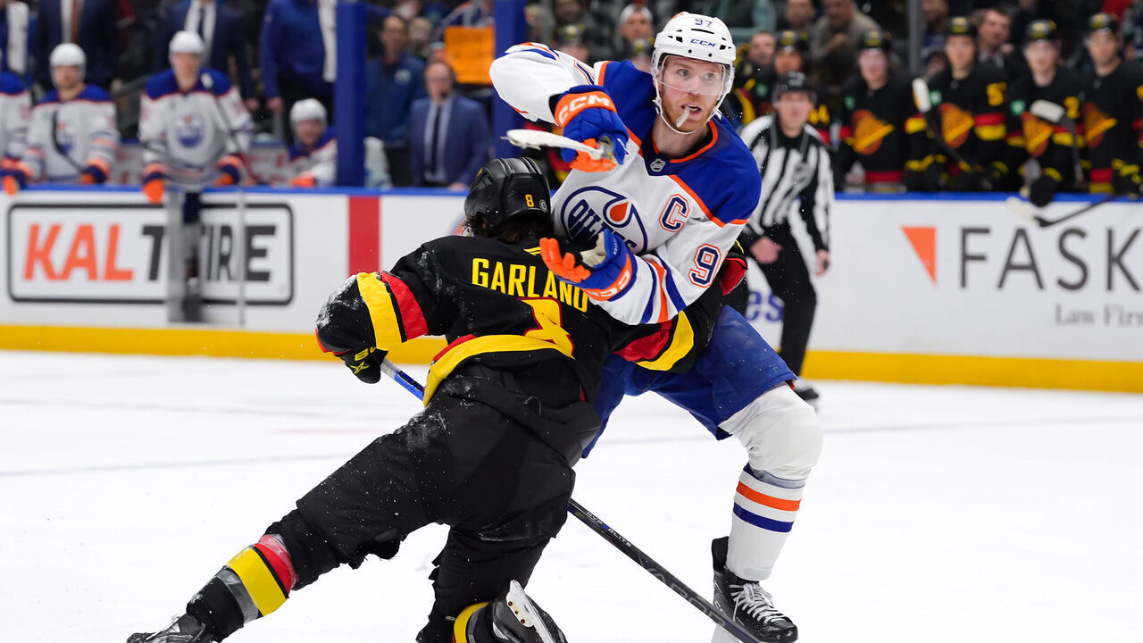 VANCOUVER, CANADA - JANUARY 18: Connor McDavid #97 of the Edmonton Oilers is checked by Conor Garland #8 of the Vancouver Canucks during the third period of their NHL game at Rogers Arena on January 18, 2025 in Vancouver, British Columbia, Canada.