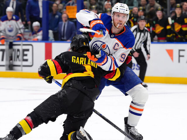 VANCOUVER, CANADA - JANUARY 18: Connor McDavid #97 of the Edmonton Oilers is checked by Conor Garland #8 of the Vancouver Canucks during the third period of their NHL game at Rogers Arena on January 18, 2025 in Vancouver, British Columbia, Canada.