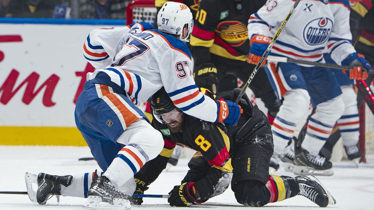 VANCOUVER, CANADA - JANUARY 18: Connor McDavid #97 of the Edmonton Oilers checks Conor Garland #8 of the Vancouver Canucks during the third period of their NHL game at Rogers Arena on January 18, 2025 in Vancouver, British Columbia, Canada. Vancouver won 3-2.