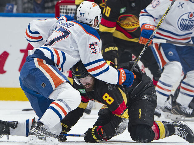 VANCOUVER, CANADA - JANUARY 18: Connor McDavid #97 of the Edmonton Oilers checks Conor Garland #8 of the Vancouver Canucks during the third period of their NHL game at Rogers Arena on January 18, 2025 in Vancouver, British Columbia, Canada. Vancouver won 3-2.