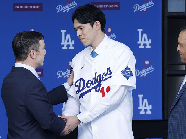 LOS ANGELES, CALIFORNIA - JANUARY 22: Pitcher Roki Sasaki (2R) shakes hands with President, Baseball Operations Andrew Friedman (2L) talk during a Los Angeles Dodgers press conference at Dodger Stadium on January 22, 2025 in Los Angeles, California.