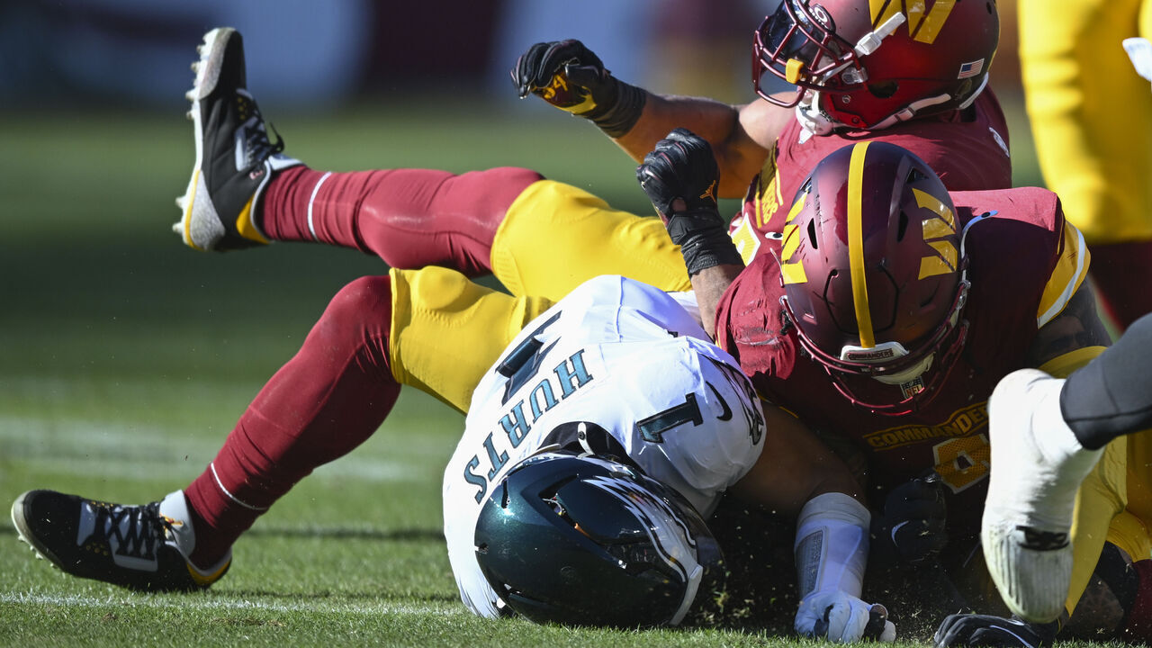 LANDOVER, MD - DECEMBER 22: Philadelphia Eagles quarterback Jalen Hurts (1) is knocked out of the game on a tackle by Washington Commanders linebacker Bobby Wagner, top and Commanders linebacker Frankie Luvu at the Northwest Stadium in Landover, MD on December 22, 2024.
