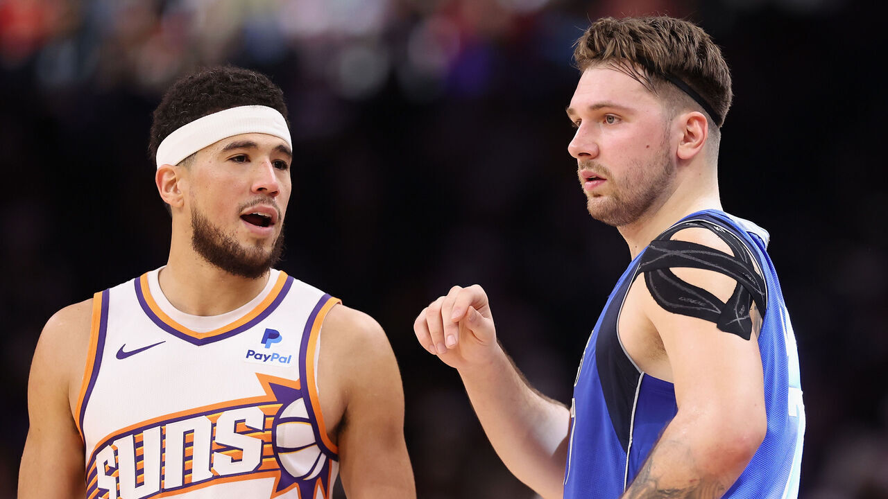 PHOENIX, ARIZONA - DECEMBER 25: Devin Booker #1 of the Phoenix Suns and Luka Doncic #77 of the Dallas Mavericks during the NBA game at Footprint Center on December 25, 2023 in Phoenix, Arizona. The Mavericks defeated the Suns 128-114.