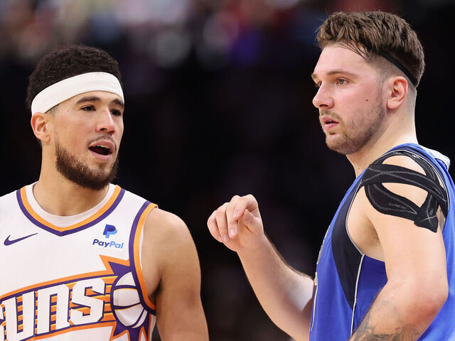 PHOENIX, ARIZONA - DECEMBER 25: Devin Booker #1 of the Phoenix Suns and Luka Doncic #77 of the Dallas Mavericks during the NBA game at Footprint Center on December 25, 2023 in Phoenix, Arizona. The Mavericks defeated the Suns 128-114.