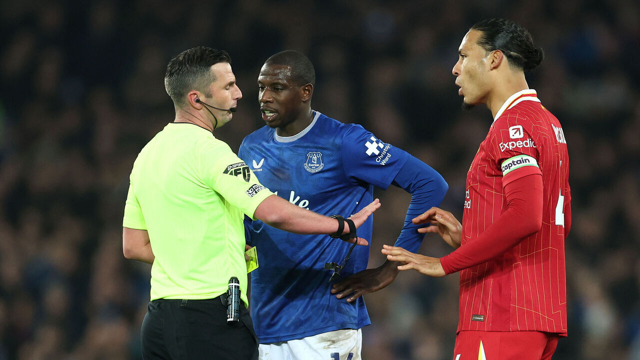 LIVERPOOL, ENGLAND - FEBRUARY 12: Abdoulaye Doucoure of Everton is shown a yellow card by referee Michael Oliver as Virgil Van Dijk watches on during the Premier League match between Everton FC and Liverpool FC at Goodison Park on February 12, 2025 in Liverpool, England.