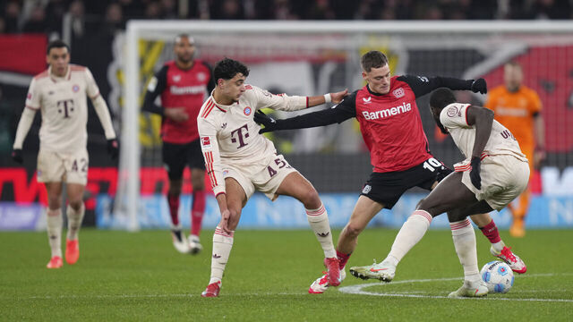 LEVERKUSEN, GERMANY - FEBRUARY 15: Florian Wirtz of Bayer 04 Leverkusen is put under pressure by Dayot Upamecano and Aleksandar Pavlovic of FC Bayern München during the Bundesliga match between Bayer 04 Leverkusen and FC Bayern München at BayArena on February 15, 2025 in Leverkusen, Germany.