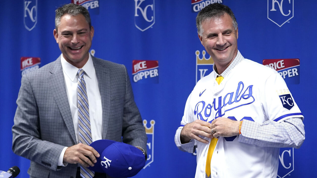 KANSAS CITY, MISSOURI - NOVEMBER 03: Matt Quatraro puts on a jersey as he is introduced as the new manager of the Kansas City Royals as general manager J.J. Picollo looks on at Kauffman Stadium on November 03, 2022 in Kansas City, Missouri.