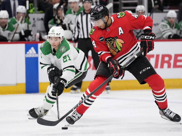 CHICAGO, ILLINOIS - APRIL 06: Seth Jones #4 of the Chicago Blackhawks skates with the puck against Jason Robertson #21 of the Dallas Stars during the third period at the United Center on April 06, 2024 in Chicago, Illinois.