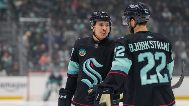 SEATTLE, WASHINGTON - NOVEMBER 22: Yanni Gourde #37 of the Seattle Kraken talks with teammate Oliver Bjorkstrand #22 before a face-off during the first period of a game against the San Jose Sharks at Climate Pledge Arena on November 22, 2023 in Seattle, Washington.