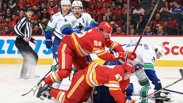 CALGARY, AB - MARCH 12: MacKenzie Weegar #52 piles on top of teammate Conor Zary #47 of the Calgary Flames during a scuffle against the Vancouver Canucks at Scotiabank Saddledome on March 12, 2025 in Calgary, Alberta, Canada.