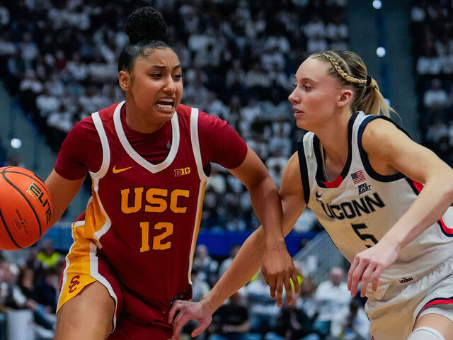 HARTFORD, CONNECTICUT - DECEMBER 21: JuJu Watkins #12 of the USC Trojans is defended by Paige Bueckers #5 and Morgan Cheli #23 of the Connecticut Huskies during the second half of an NCAA women's basketball game at the XL Center on December 21, 2024 in Hartford, Connecticut.