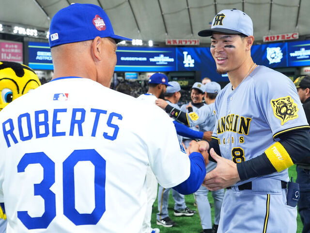 TOKYO, JAPAN - MARCH 16: Teruaki Sato #8 of the Hanshin Tigers is congratulated by Manager Dave Roberts #30 of the Los Angeles Dodgers after the game at Tokyo Dome on March 16, 2025 in Tokyo, Japan.