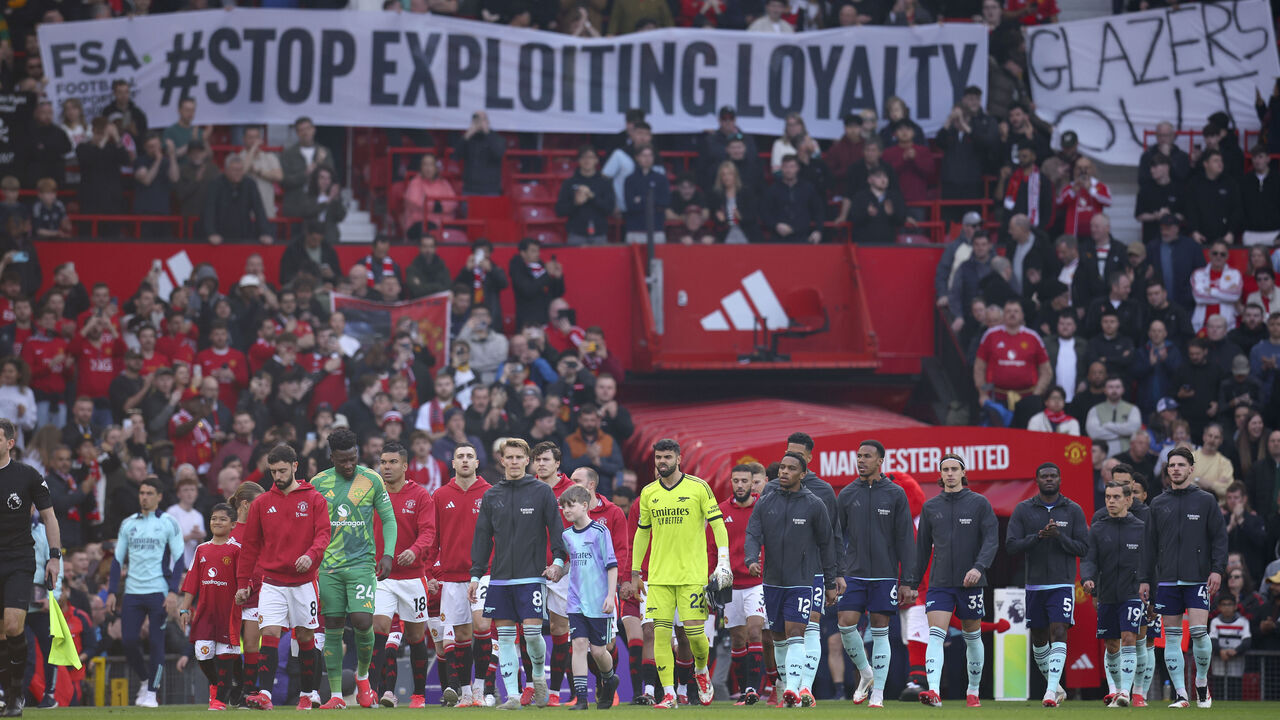 MANCHESTER, ENGLAND - MARCH 9: Players walk out under a fan banner in the crowd the Premier League match between Manchester United FC and Arsenal FC at Old Trafford on March 9, 2025 in Manchester, England.