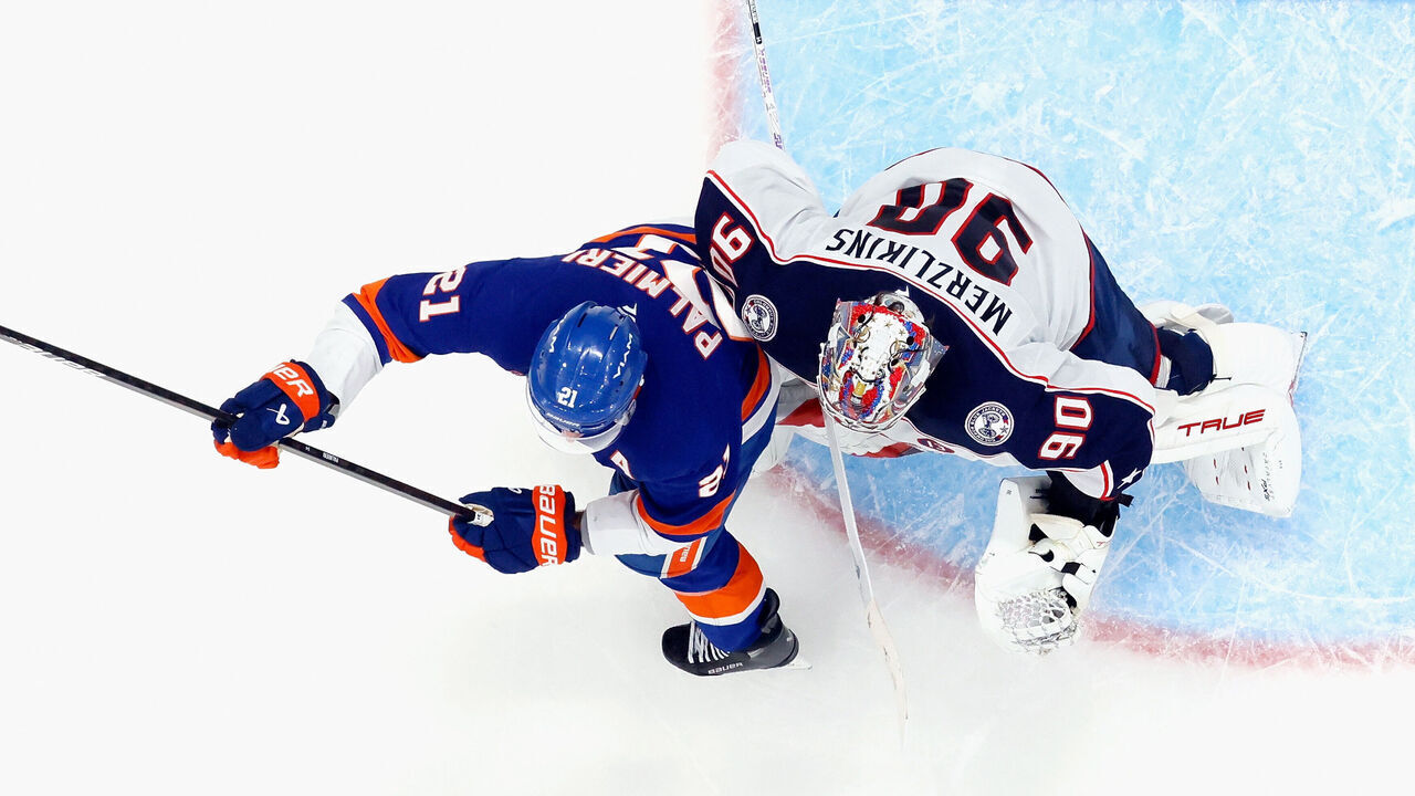 ELMONT, NEW YORK - MARCH 24: Kyle Palmieri #21 of the New York Islanders bumps Elvis Merzlikins #90 of the Columbus Blue Jackets in overtime which led to a disallowed goal at UBS Arena on March 24, 2025 in Elmont, New York. The Blue Jackets defeated the Islanders 4-3 in overtime.
