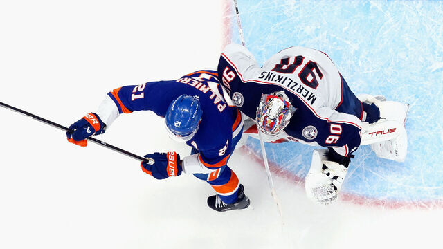 ELMONT, NEW YORK - MARCH 24: Kyle Palmieri #21 of the New York Islanders bumps Elvis Merzlikins #90 of the Columbus Blue Jackets in overtime which led to a disallowed goal at UBS Arena on March 24, 2025 in Elmont, New York. The Blue Jackets defeated the Islanders 4-3 in overtime.