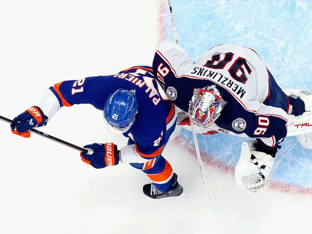 ELMONT, NEW YORK - MARCH 24: Kyle Palmieri #21 of the New York Islanders bumps Elvis Merzlikins #90 of the Columbus Blue Jackets in overtime which led to a disallowed goal at UBS Arena on March 24, 2025 in Elmont, New York. The Blue Jackets defeated the Islanders 4-3 in overtime.