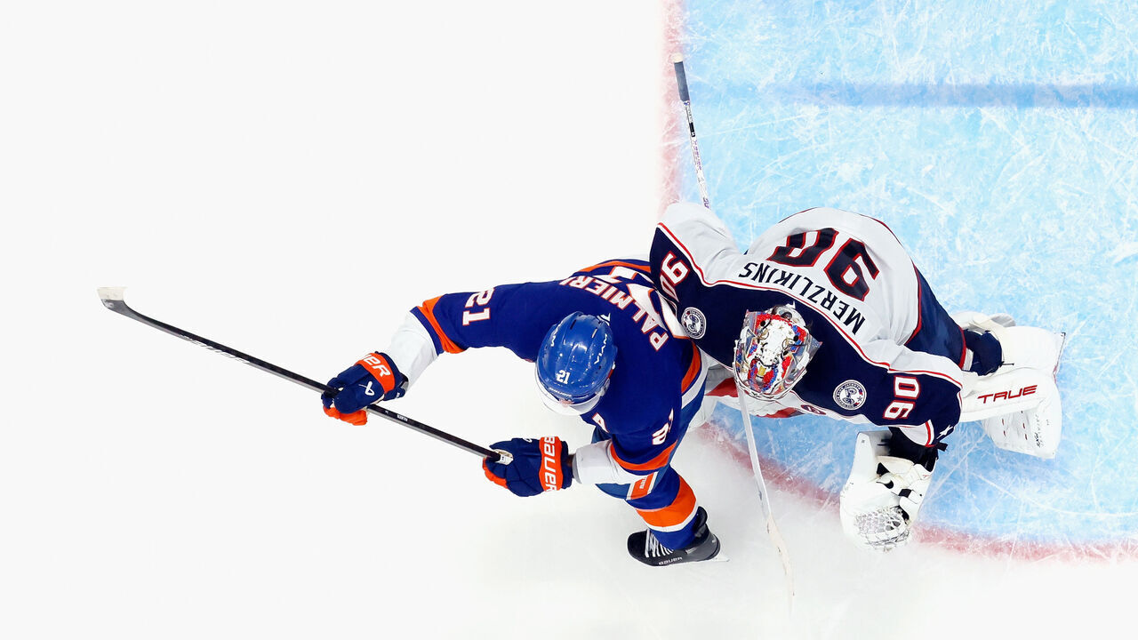 ELMONT, NEW YORK - MARCH 24: Kyle Palmieri #21 of the New York Islanders bumps Elvis Merzlikins #90 of the Columbus Blue Jackets in overtime which led to a disallowed goal at UBS Arena on March 24, 2025 in Elmont, New York. The Blue Jackets defeated the Islanders 4-3 in overtime.