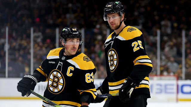BOSTON, MASSACHUSETTS - DECEMBER 21: Brad Marchand #63 of the Boston Bruins and Brandon Carlo #25 look on during the first period against the Buffalo Sabres at TD Garden on December 21, 2024 in Boston, Massachusetts.