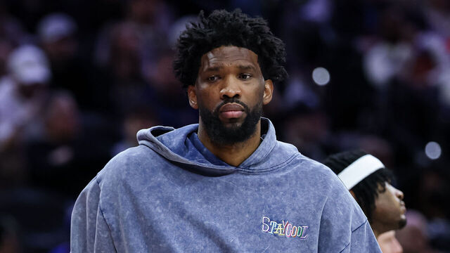 PHILADELPHIA, PENNSYLVANIA - MARCH 01: Joel Embiid #21 of the Philadelphia 76ers dribbles a ball while wearing street clothes on the bench during the second half of the game against the Golden State Warriors at the Wells Fargo Center on March 1, 2025 in Philadelphia, Pennsylvania.