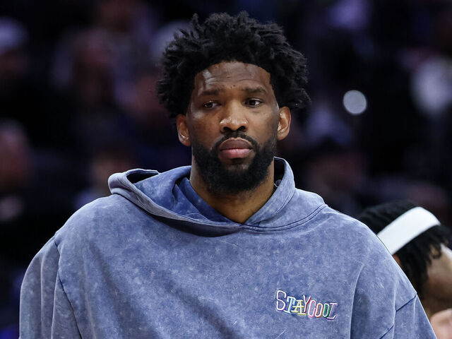 PHILADELPHIA, PENNSYLVANIA - MARCH 01: Joel Embiid #21 of the Philadelphia 76ers dribbles a ball while wearing street clothes on the bench during the second half of the game against the Golden State Warriors at the Wells Fargo Center on March 1, 2025 in Philadelphia, Pennsylvania.
