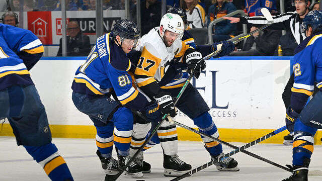 ST. LOUIS, MO - APRIL 3: Dylan Holloway #81 of the St. Louis Blues defends against Bryan Rust #17 of the Pittsburgh Penguins on April 3, 2025 at the Enterprise Center in St. Louis, Missouri.