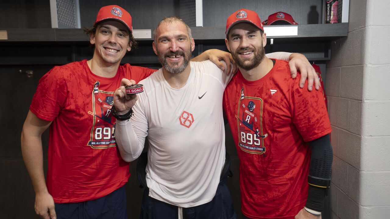 ELMONT, NEW YORK - APRIL 6: Alex Ovechkin #8 of the Washington Capitals poses for a photo with the puck from his 895th career goal with Dylan Strome #17 and Tom Wilson #43, who assisted the goal, in the locker room after a game against the New York Islanders at UBS Arena on April 6, 2025 in Elmont, New York. With this goal, Ovechkin passes Wayne Gretzky for the all-time goal scoring record.