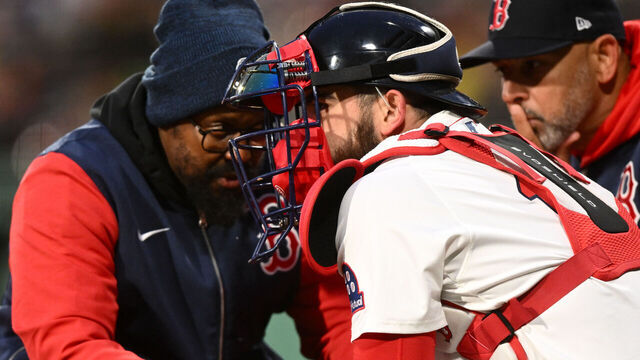 BOSTON, MASSACHUSETTS - APRIL 07: A Boston Red Sox trainer checks on Connor Wong #12 after injuring his hand during the first inning against the Toronto Blue Jays at Fenway Park on April 07, 2025 in Boston, Massachusetts.