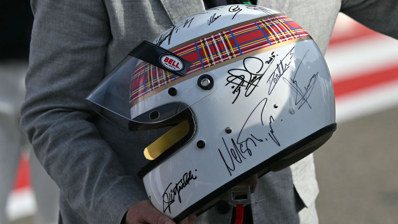 Marc Stewart holds the helmet of his father, the former British Formula One racing driver Jackie Stewart, after the latter performed an exhibition lap ahead of the Bahrain Formula One Grand Prix at the Bahrain International Circuit in Sakhir on April 13, 2025.