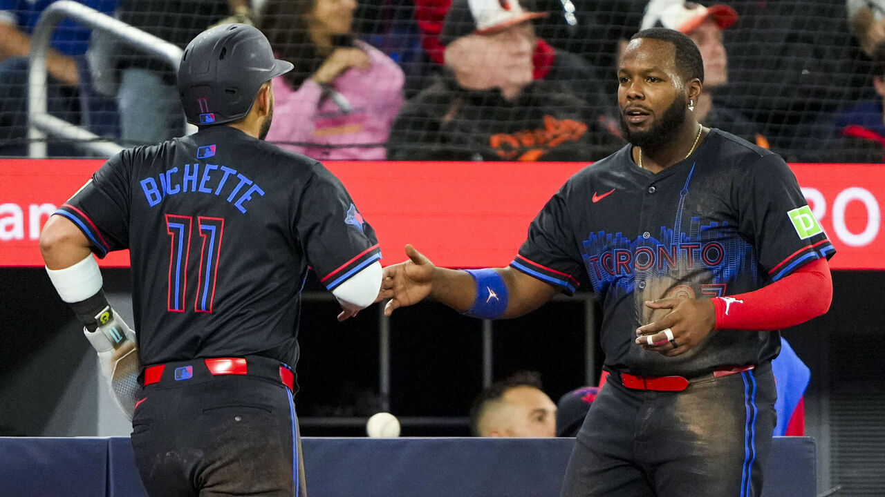 TORONTO, CANADA - MARCH 28: Bo Bichette #11 of the Toronto Blue Jays celebrates with teammate Vladimir Guerrero Jr. #27 after scoring against the Baltimore Orioles during the fourth inning at Rogers Centre on March 28, 2025 in Toronto, Canada.