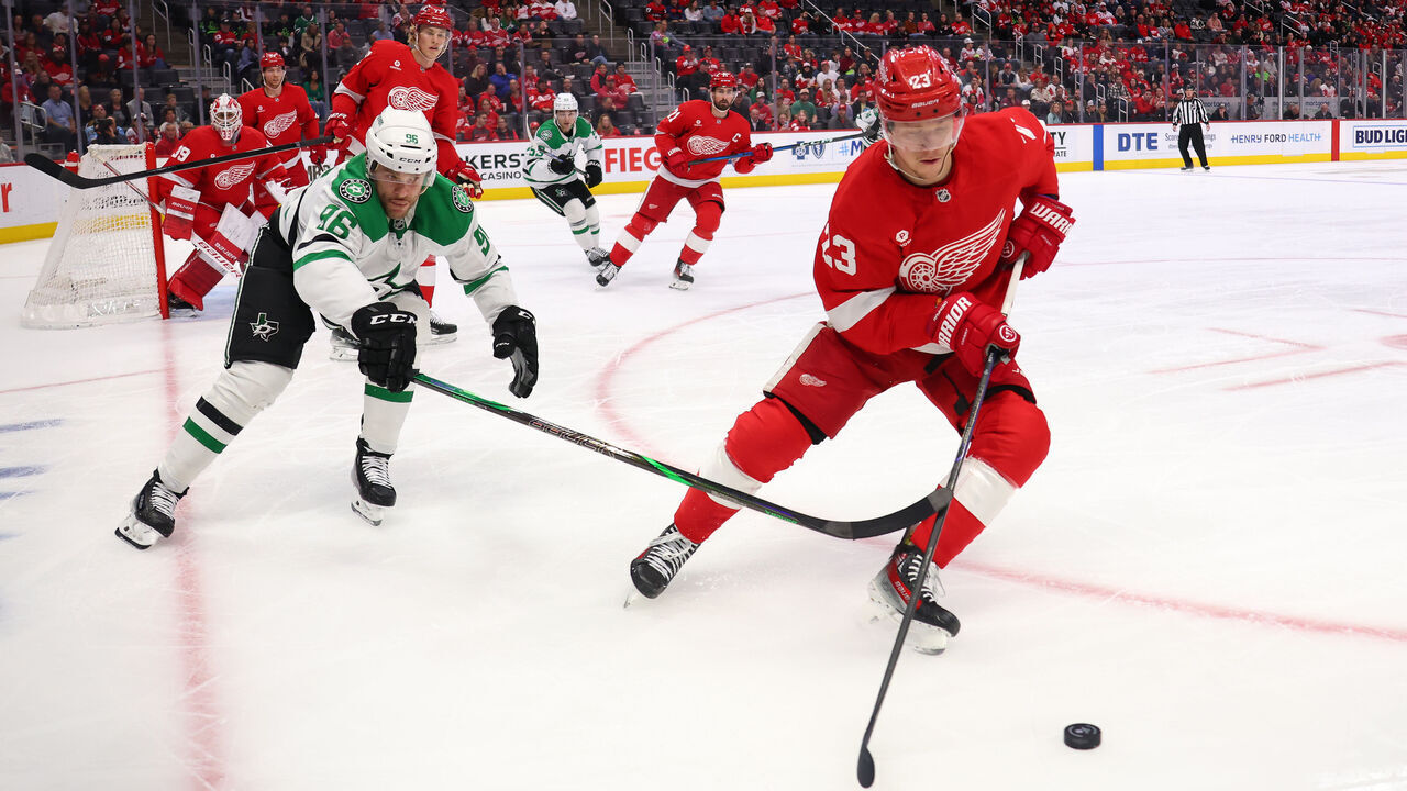 DETROIT, MICHIGAN - APRIL 14: Lucas Raymond #23 of the Detroit Red Wings tries to get around the stick of Mikko Rantanen #96 of the Dallas Stars during the first period at Little Caesars Arena on April 14, 2025 in Detroit, Michigan.