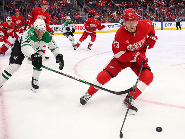 DETROIT, MICHIGAN - APRIL 14: Lucas Raymond #23 of the Detroit Red Wings tries to get around the stick of Mikko Rantanen #96 of the Dallas Stars during the first period at Little Caesars Arena on April 14, 2025 in Detroit, Michigan.