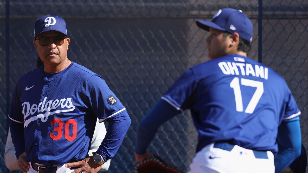 GLENDALE, ARIZONA - FEBRUARY 15: Manager Dave Roberts #30 of the Los Angeles Dodgers looks on as pitcher Shohei Ohtani #17 throws in the bullpen during a team workout at Camelback Ranch on February 15, 2025 in Glendale, Arizona.
